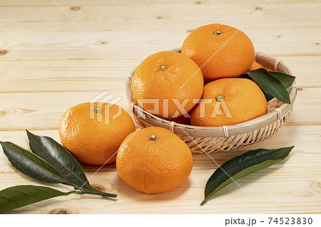 木目のテーブルに葉を添えて置いたみかん 74523830