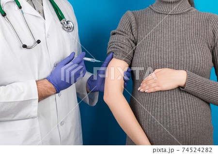 Newborn family concept. A pregnant woman with the hand of a doctor to vaccinate ,nurse vaccinating young girl having a child or young developing in the uterus 74524282
