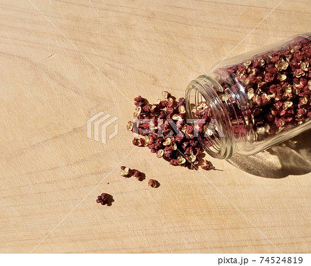 ガラス瓶からこぼれた四川赤山椒のホールの写真素材
