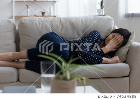 Depressed young asian woman lie on couch cry feel bad 74524888