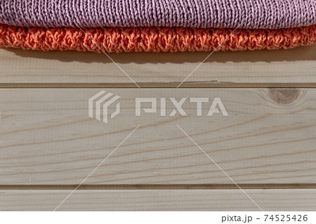 knitted folded clothes of purple and coral color on light wooden background, concept of natural things knitted folded clothes of purple and coral color on light wooden background, concept of natural things 74525426