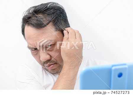 Asian middle man using tweezers to pluck his gray hair isolated Asian middle man using tweezers to pluck his gray hair isolated 74527273