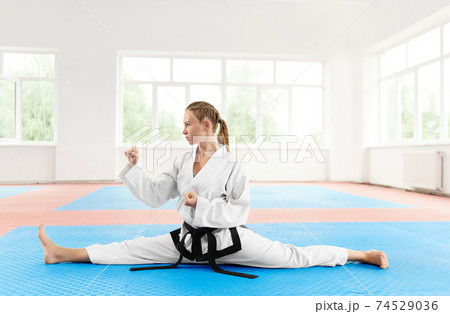 Girl doing stretch twine with clenched fist in light gym. Girl doing stretch twine with clenched fist in light gym. 74529036