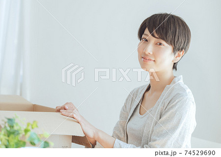 自宅で荷物を確認するパジャマ姿の若い女性 74529690