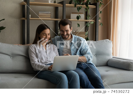Young family couple sit by laptop discuss flat renovation options Young family couple sit by laptop discuss flat renovation options 74530272