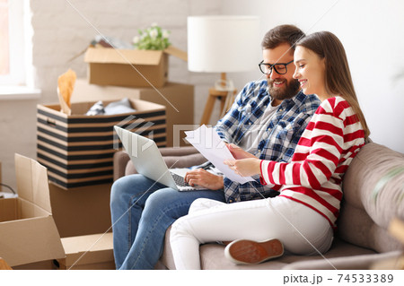 Cheerful couple with laptop discussing insurance of new home 74533389