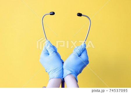 Doctor's hands in gloves hold stethoscope closeup Doctor's hands in gloves hold stethoscope closeup 74537095
