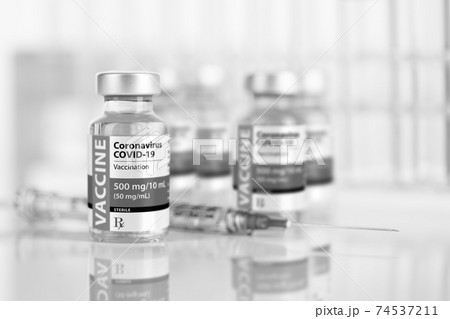 Coronavirus COVID-19 Vaccine Vials and Syringe On Reflective Surface 74537211