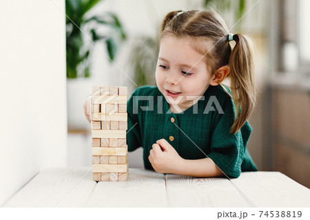 Little cute preschool girl plays at home with wood toys on table. Natural tactility development 74538819