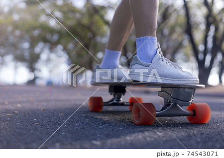 Close-up Asian women surf skate or skateboard outdoors on beautiful morning. Happy young women play surf skate at park on morning time. Close up Asian women leg wear sneaker paly surf skate on public Close-up Asian women surf skate or skateboard outdoors on beautiful morning. Happy young women play surf skate at park on morning time. Close up Asian women leg wear sneaker paly surf skate on public 74543071