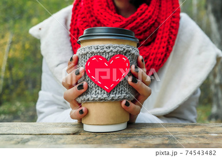 Close up cozy cup with heart shape in hand on the nature. Outdoor picnic good mood. 74543482