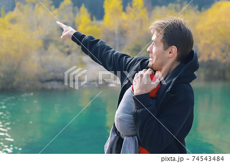 Attractive young father with her infant baby in sling outdoor. Man is carrying her child and travel in autumn mountain lake. Babywearing concept Attractive young father with her infant baby in sling outdoor. Man is carrying her child and travel in autumn mountain lake. Babywearing concept 74543484