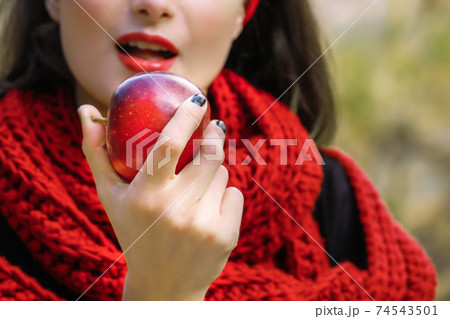 A young woman is eating a ripe red apple. The forbidden fruit. A young woman is eating a ripe red apple. The forbidden fruit. 74543501