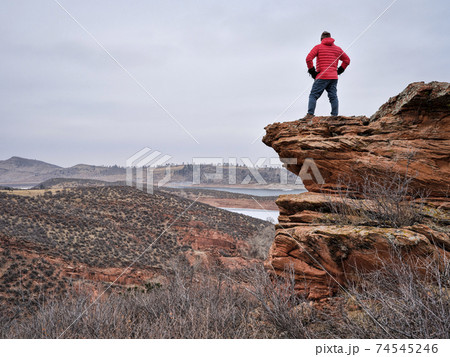 male hiker on a rocky cliff  at foothills of Rocky Mountains 74545246