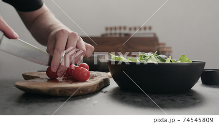 man cut cherry tomato for salad on kitchen countertop man cut cherry tomato for salad on kitchen countertop 74545809