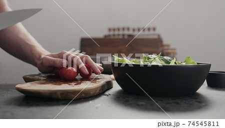 man cut cherry tomato for salad on kitchen countertop man cut cherry tomato for salad on kitchen countertop 74545811