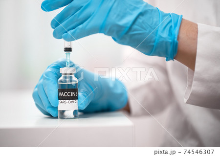Doctor dials the vaccine into a syringe 74546307