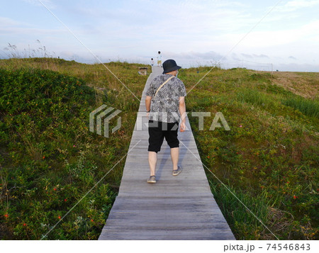 真っ直ぐな一本道を歩く男性の後ろ姿の写真素材