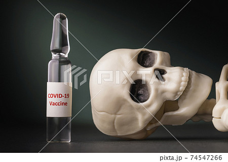 Ampoule with a vaccine against coronavirus and a human skeleton on the table, close-up. Concept of drug efficacy against the COVID-19 pandemic Ampoule with a vaccine against coronavirus and a human skeleton on the table, close-up. Concept of drug efficacy against the COVID-19 pandemic 74547266