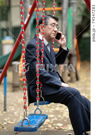 電話をするビジネスマン　公園ブランコ 74547283