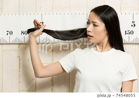 髪の毛の長さを測る女性の写真素材