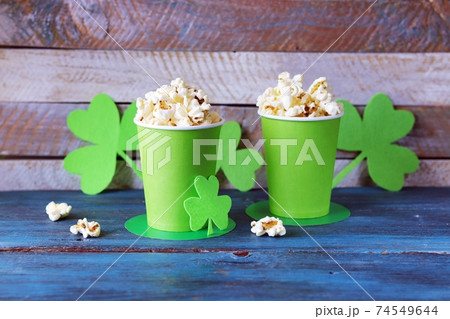 Popcorn in green paper cups in the shape of St. Patrick's hat, shamrock on a wooden table, party, congratulation, postcard Popcorn in green paper cups in the shape of St. Patrick's hat, shamrock on a wooden table, party, congratulation, postcard 74549644