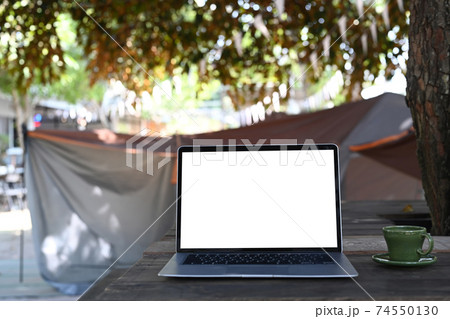 Mock up laptop computer with blank screen on folding picnic table near camp tent outdoors. Mock up laptop computer with blank screen on folding picnic table near camp tent outdoors. 74550130