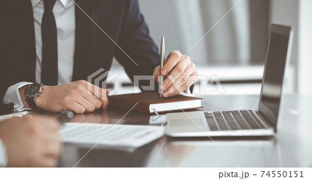 Unknown businessmen and woman sitting, working and discussing questions at meeting in modern office, close-up 74550151