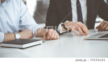 Unknown business people using laptop computer at the desk in modern office. Businessman or male entrepreneur is working with his colleague. Teamwork and partnership concept 74550191