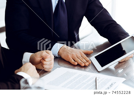 Business people using tablet computer while working together in modern office. Unknown businessman with colleague at workplace. Teamwork and partnership concept Business people using tablet computer while working together in modern office. Unknown businessman with colleague at workplace. Teamwork and partnership concept 74552228