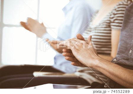 Business people clapping at meeting or conference, close-up of hands. Group of unknown businessmen and women in modern white office. Success teamwork, corporate coaching and applause concept Business people clapping at meeting or conference, close-up of hands. Group of unknown businessmen and women in modern white office. Success teamwork, corporate coaching and applause concept 74552289