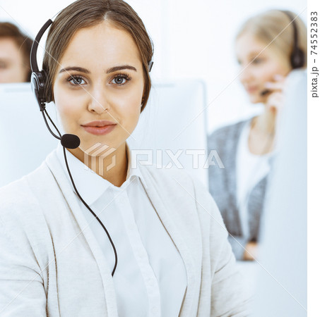 Call center. Group of diverse operators at work. Beautiful woman in headset communicating with customers of telemarketing service. Business concept 74552383