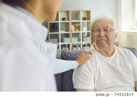 Family doctor visiting, supporting, and encouraging his or her elderly patient at home. 74552814