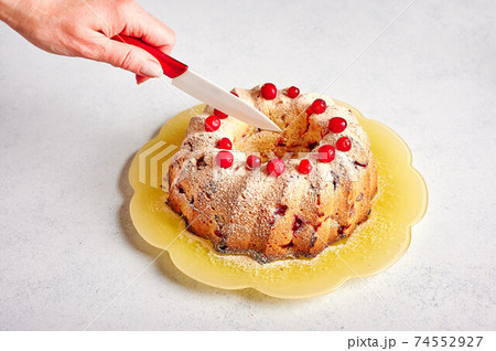 Woman's hand cuts with a knife homemade curd muffin with cranberries and orange zest 74552927