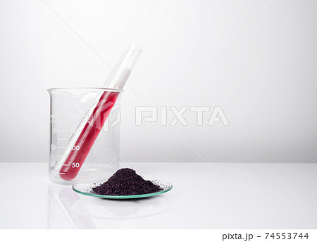 Potassium Permanganate Liquid in test tube place next to KMnO4 on chemical watch glass. Cosmetic chemicals ingredient on white laboratory table. 74553744