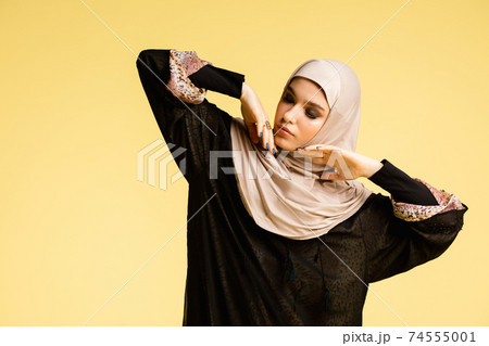 Beautiful arab woman posing in stylish hijab isolated on yellow studio background. Fashion, beauty, style concept Beautiful arab woman posing in stylish hijab isolated on yellow studio background. Fashion, beauty, style concept 74555001