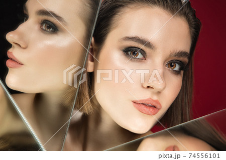 Portrait of female fashion model with reflections on mirrors around her face. Style and beauty concept. Close up. 74556101