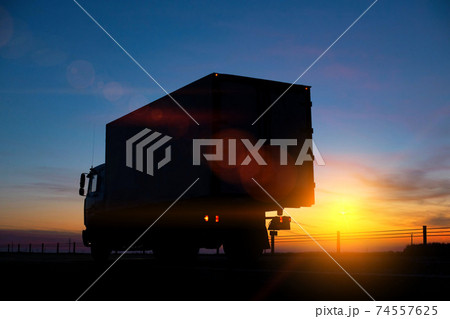 Truck driver transports cargo on a truck against the backdrop of sunset at night. The concept of compliance with the work and rest regime of drivers 74557625