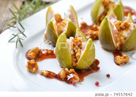 Baked figs stuffed with goats cream cheese and candied walnuts with sweet honey and rosemary Baked figs stuffed with goats cream cheese and candied walnuts with sweet honey and rosemary 74557642