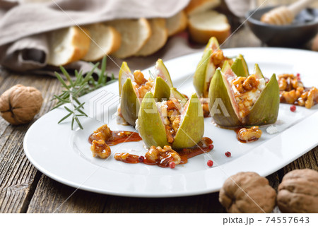 Baked figs stuffed with goats cream cheese and candied walnuts with sweet honey and rosemary Baked figs stuffed with goats cream cheese and candied walnuts with sweet honey and rosemary 74557643