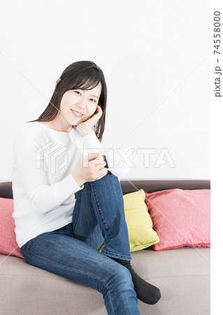 ソファの上でホットコーヒーを飲む女性 74558000