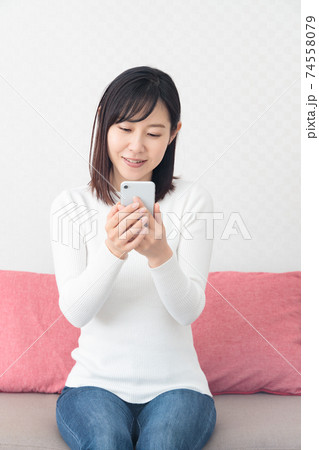 ソファに座ってスマホを持つ女性 ソファに座ってスマホを持つ女性 74558079
