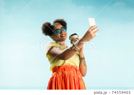 Portrait of female fashion model on blue sky background. Style and beauty concept, bright appearance Portrait of female fashion model on blue sky background. Style and beauty concept, bright appearance 74559403