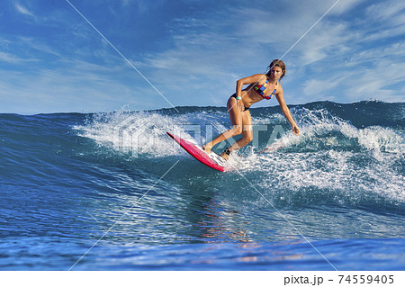 Female surfer on a blue wave Female surfer on a blue wave 74559405
