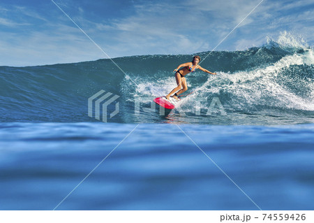 Female surfer on a blue wave Female surfer on a blue wave 74559426