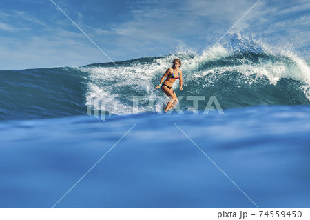 Female surfer on a blue wave Female surfer on a blue wave 74559450