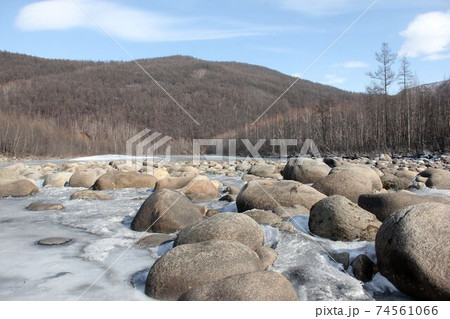 A river in Yakutia with large stones. The river in Yakutia, against the background of the forest. A river in the north in summer. 74561066