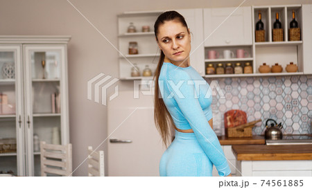 Beautiful woman in sports uniform is preparing for sports training at home 74561885