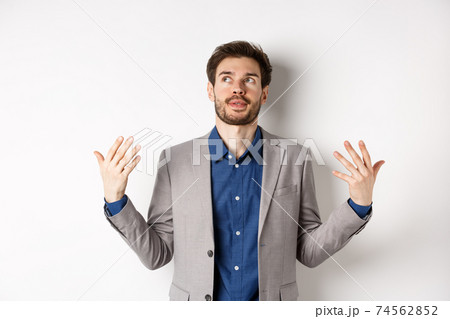 Tensed young manager in suit need some air, waving at himself as feeling flushed and annoyed, standing on white background Tensed young manager in suit need some air, waving at himself as feeling flushed and annoyed, standing on white background 74562852