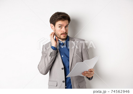 Confused office worker in suit scratching beard and look clueless, cant understand document, holding paper with indecisive face, white background Confused office worker in suit scratching beard and look clueless, cant understand document, holding paper with indecisive face, white background 74562946